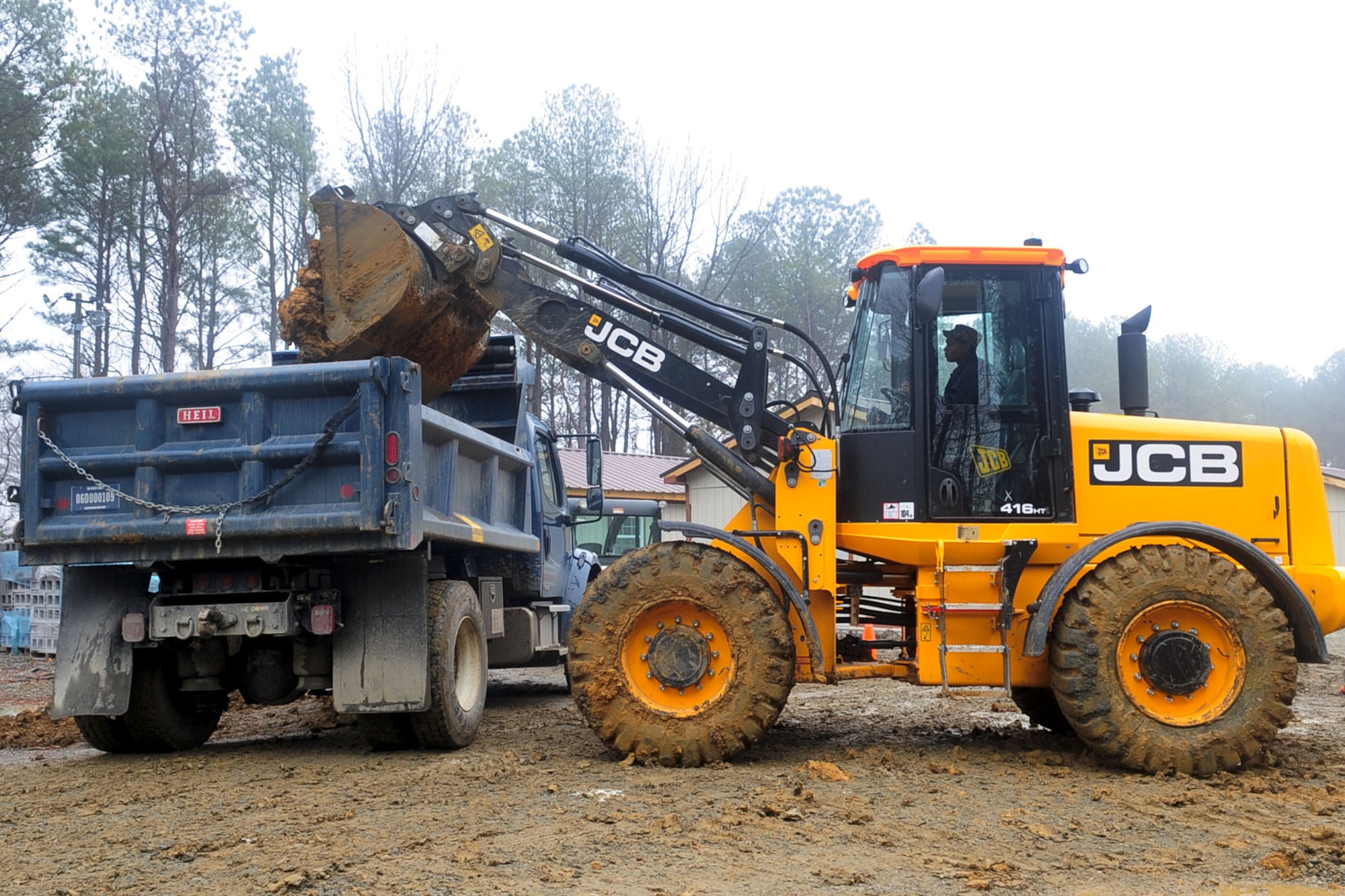 U.S. Air Force Airman 1st Class DaQuan Price, 633rd Civil Engineer Squadron heavy equipment operator, discards excess mud into a dump truck at Langley Air Force Base, Va., Jan., 23, 2012. Members of the 633rd CES are rebuilding Raptor Town to provide a more realistic deployment simulation area for training personnel. (U.S. Air Force photo by Staff Sgt. Ashley Hawkins/Released)