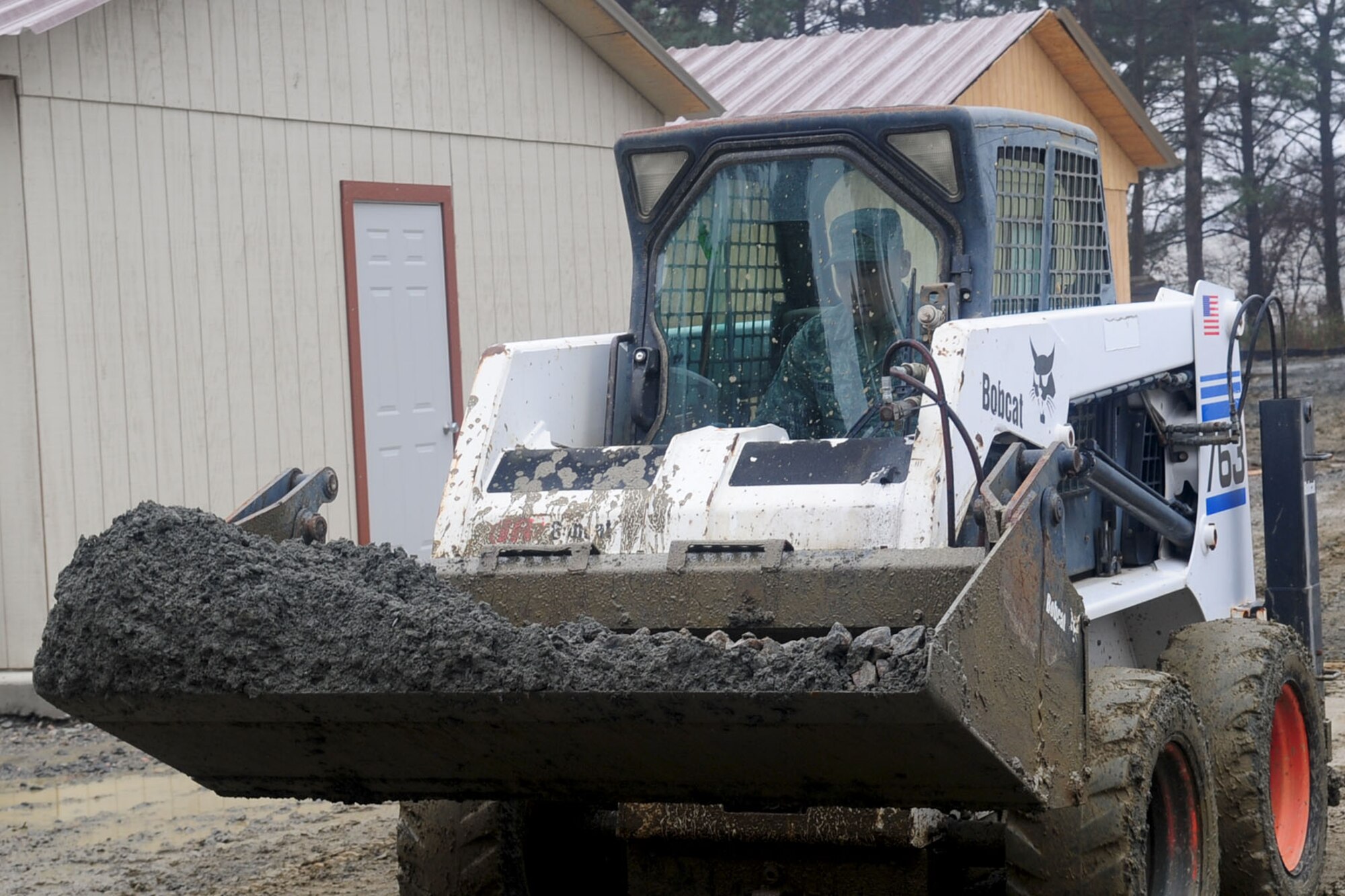 U.S. Air Force Senior Airman Lloyd Swede, 633rd Civil Engineer Squadron, heavy equipment operator, drives a skid steer, used to load and level the mud, at Langley Air Force Base, Va., Jan. 23, 2012. Raptor Town construction has a projected completion date of Feb. 3.  (U.S. Air Force photo by Staff Sgt. Ashley Hawkins/Released)