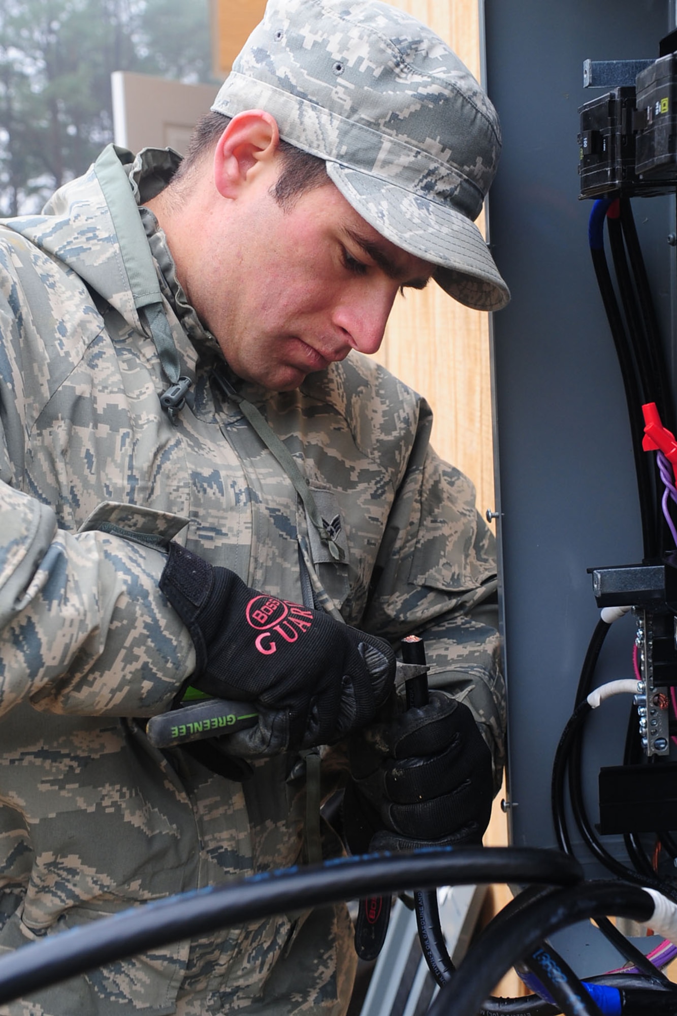 U.S. Air Force Senior Airman Sean Alberts, 633rd Civil Engineer Squadron, electrical apprentice, strips wires while placing them in the primary electric panel at Langley Air Force Base, Va., Jan. 23, 2012. The buildings in the newly renovated Raptor Town will be equipped with beds, heating, and air conditioning. (U.S. Air Force photo by Staff Sgt. Ashley Hawkins/Released)