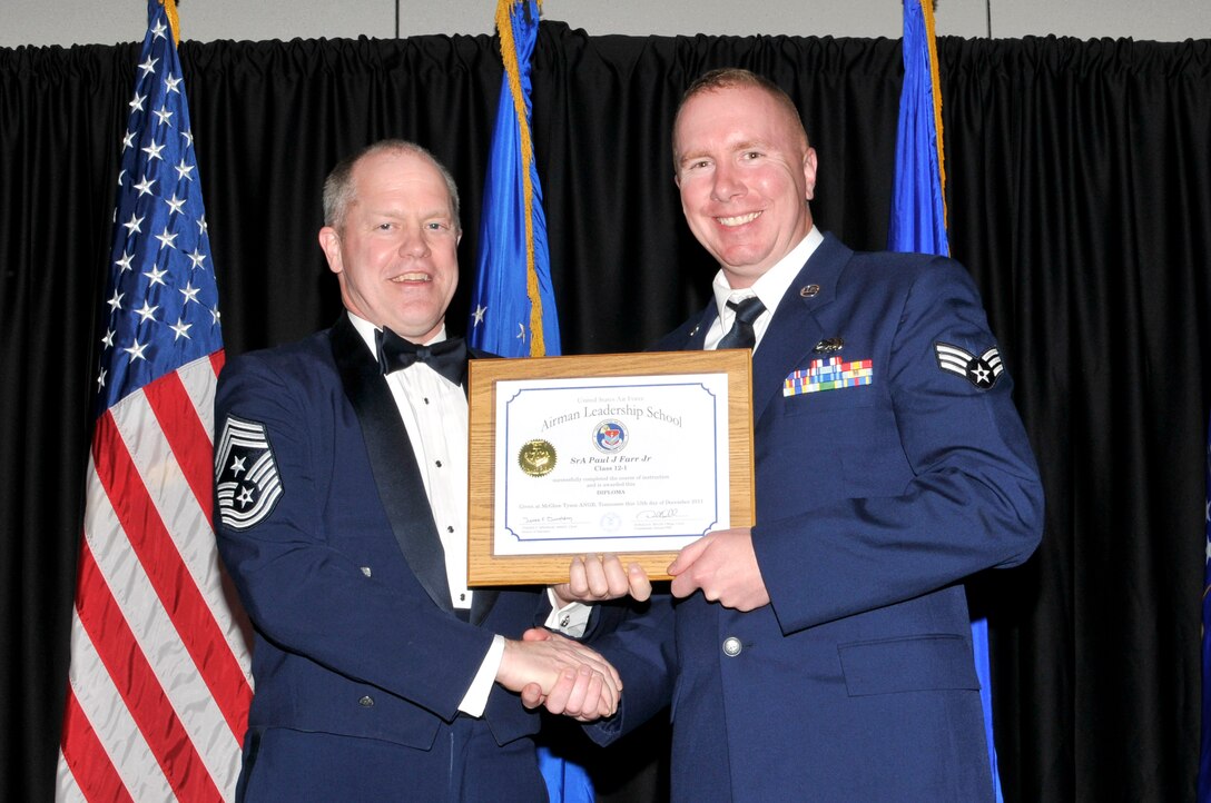 McGHEE TYSON AIR NATIONAL GUARD BASE, Tenn. - Senior Airman Paul J. Farr Jr, right, receives the distinguished graduate award for Airman Leadership School Class 12-1, at The I.G. Brown Air National Guard Training and Education Center from the Air National Guard Command Chief Master Sgt. Christopher E. Muncy, Dec. 13, 2011.  The distinguished graduate award is presented to students in the top ten percent of the class.  It is based on objective and performance evaluations, demonstrated leadership, and performance as a team player. (U.S. Air Force photo by Master Sgt. Kurt Skoglund/Released)