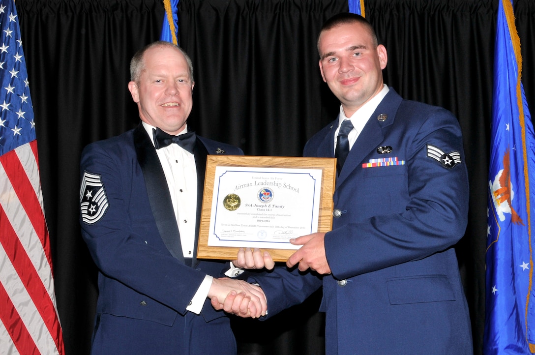 McGHEE TYSON AIR NATIONAL GUARD BASE, Tenn. - Senior Airman Joseph E. Tandy, right, receives the distinguished graduate award for Airman Leadership School Class 12-1, at The I.G. Brown Air National Guard Training and Education Center from the Air National Guard Command Chief Master Sgt. Christopher E. Muncy, Dec. 13, 2011.  The distinguished graduate award is presented to students in the top ten percent of the class.  It is based on objective and performance evaluations, demonstrated leadership, and performance as a team player. (U.S. Air Force photo by Master Sgt. Kurt Skoglund/Released)