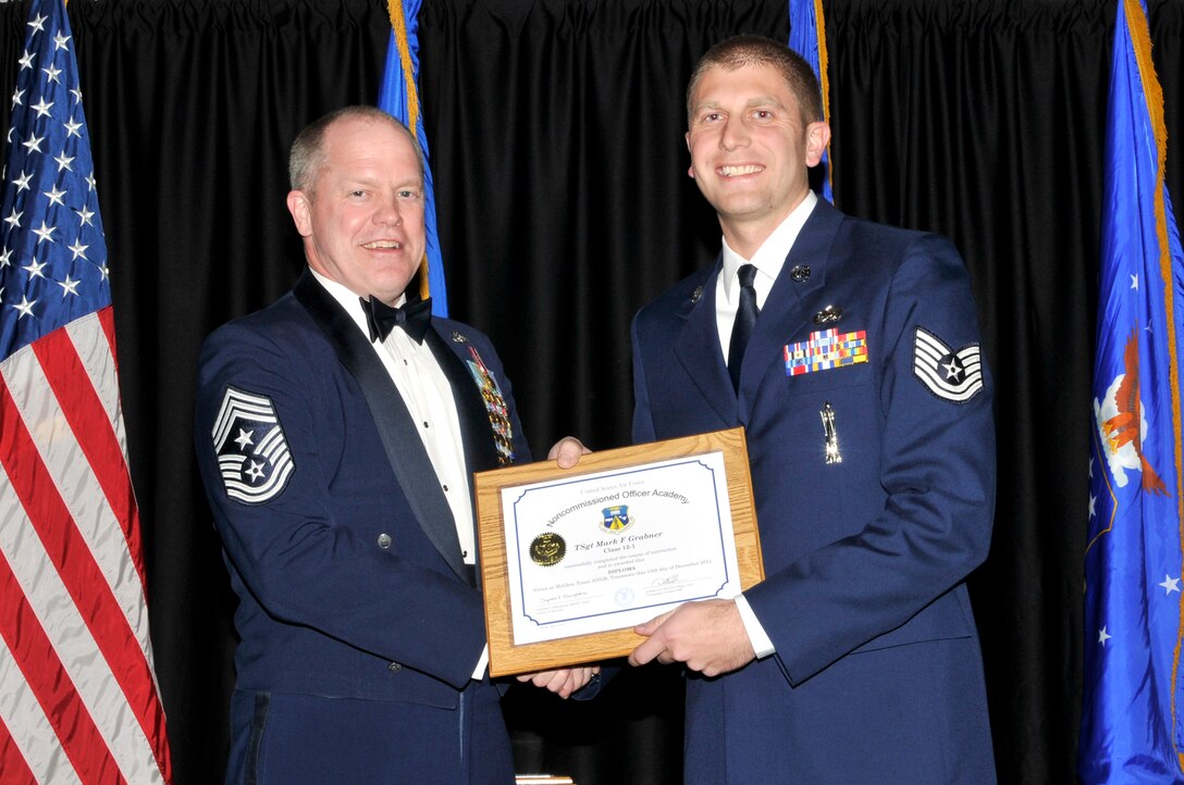 McGHEE TYSON AIR NATIONAL GUARD BASE, Tenn. - Tech. Sgt. Mark F. Grabner, right, receives the distinguished graduate award for Satellite NCO Academy Class 12-1 at The I.G. Brown Air National Guard Training and Education Center from Air National Guard Command Chief Master Sgt. Christopher E. Muncy, Dec. 13, 2011. The distinguished graduate award is presented to students in the top ten percent of the class.  It is based on objective and performance evaluations, demonstrated leadership, and performance as a team player. (U.S. Air Force photo by Master Sgt. Kurt Skoglund/Released)
