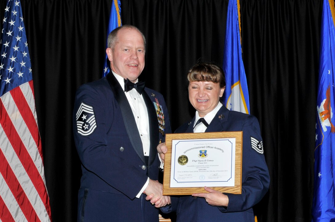 McGHEE TYSON AIR NATIONAL GUARD BASE, Tenn. - Tech. Sgt. Sara E. Coney, right, receives the distinguished graduate award for Satellite NCO Academy Class 12-1 at The I.G. Brown Air National Guard Training and Education Center from Air National Guard Command Chief Master Sgt. Christopher E. Muncy, Dec. 13, 2011. The distinguished graduate award is presented to students in the top ten percent of the class.  It is based on objective and performance evaluations, demonstrated leadership, and performance as a team player. (U.S. Air Force photo by Master Sgt. Kurt Skoglund/Released)