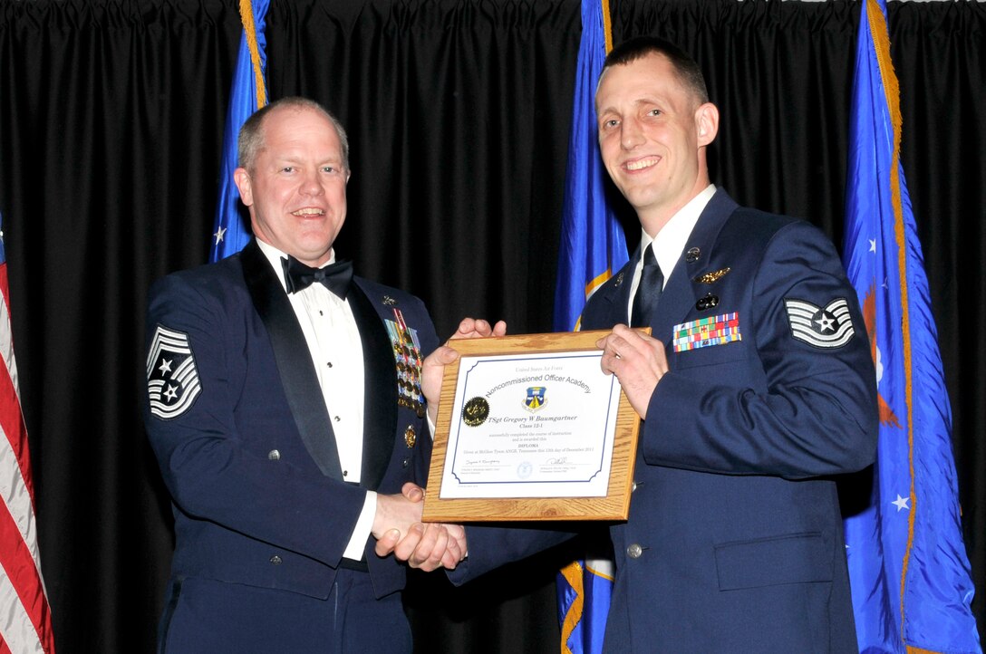 McGHEE TYSON AIR NATIONAL GUARD BASE, Tenn. - Tech. Sgt. Gregory W. Baumgartner, right, receives the distinguished graduate award for Satellite NCO Academy Class 12-1 at The I.G. Brown Air National Guard Training and Education Center from Air National Guard Command Chief Master Sgt. Christopher E. Muncy, Dec. 13, 2011. The distinguished graduate award is presented to students in the top ten percent of the class.  It is based on objective and performance evaluations, demonstrated leadership, and performance as a team player. (U.S. Air Force photo by Master Sgt. Kurt Skoglund/Released)