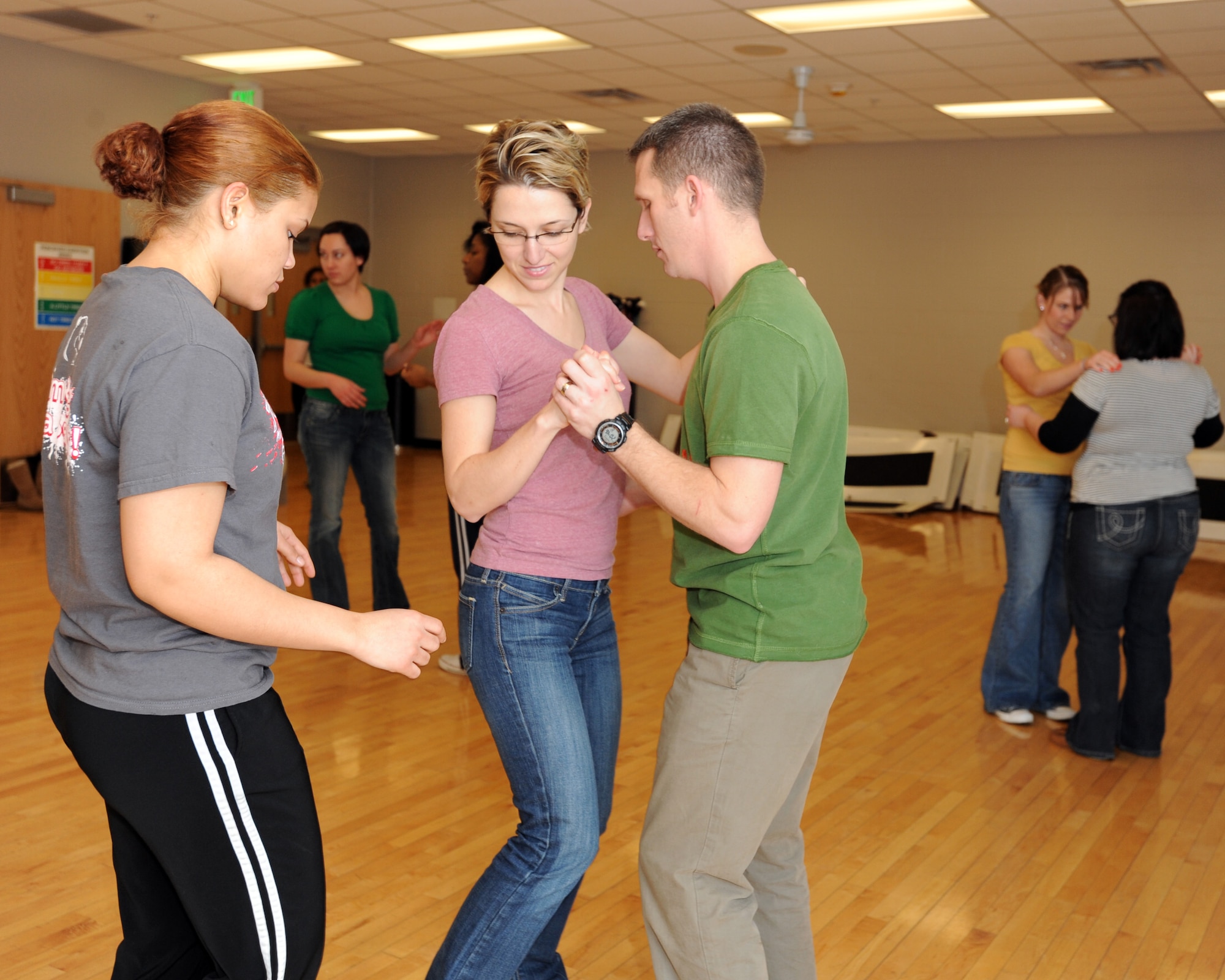 MINOT AIR FORCE BASE, N.D. -- Airman 1st Class Rina Tatis, 5th Force Support Squadron chef, explains to 1st Lt. Joseph McNamara, 91st Operations Support Squadron missile procedures training officer and spouse Filiz McNamara, the proper leg movements for dancing Salsa, during a night of Latin dance lessons at the McAdoo Sports and Fitness Center Jan 23. Classes like these offer Airmen and their families the opportunity to go out and experience new activities, especially during the cold winter months in Minot. Free Latin dance lessons are offered at the Fitness Center every Monday and Thursday from 8-9 p.m. Individuals wanting to learn how to dance popular Latin American music genres to include Bachata, Merengue, and Salsa are welcome to attend. (U.S. Air Force photo/Senior Airman Jose L. Hernandez)