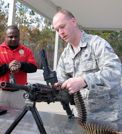 Technical Sgt. Ben Watrous rushes to load a M240B as Petty Officer 2nd Class Fredrick Favors times him during a crew-serve weapons stress-test training at the Federal Law Enforcement Training Center at Joint Base Charleston-Weapons Station, Jan. 19. Watrous properly loaded and fired off a dummy round within 23 seconds. Watrous is assigned to the 628th Security Forces Squadron and Favors is a Master-at-Arms assigned to the 628th SFS. (U.S. Navy photo/Petty Officer 2nd Class Jennifer Hudson