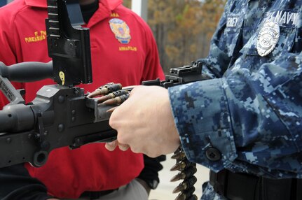 Petty Officer 3rd Class Michael Harkey loads a M240B with dummy rounds through a feed tray with guidance from Petty Officer 2nd Class Fredrick Favors during a crew-serve weapons stress-test training at the Federal Law Enforcement Training Center at Joint Base Charleston - Weapons Station, Jan. 19. The timed test served as a simulation of a real-life scenario requiring members to react, load and fire their weapon within 30 seconds. Harkey and Favors are both Master-at-Arms assigned to the 628th Security Forces Squadron. (U.S. Navy photo/Petty Officer 2nd Class Jennifer Hudson)