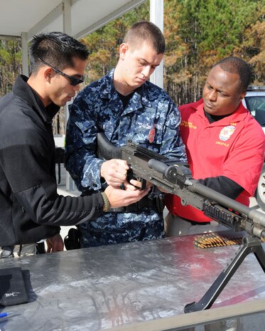 Petty officer 2nd Class Bradley Nguyen (left) and Petty Officer 2nd Class Fredrick Favors (right), instruct Petty Officer 3rd Class Michael Harkey on how to properly handle, load and fire a M240B during crew-serve weapons stress-test training at the Federal Law Enforcement Training Center at Joint Base Charleston - Weapons Station, Jan. 19. The timed test requires crew members to react, load and fire their weapon within 30 seconds. Nguyen is a Gunner’s Mate assigned to the 628th Security Forces Squadron, Favors and Harkey are Master-at-Arms assigned to the 628th SFS. (U.S. Navy photo/Petty Officer 2nd Class Jennifer Hudson)