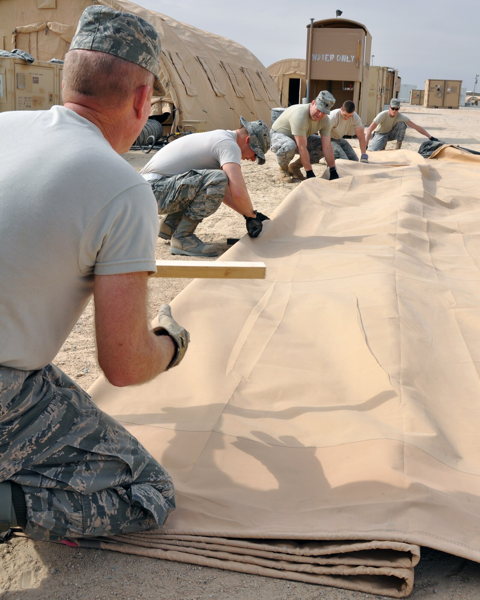 Airmen with the 386th Air Expeditionary Wing meticulously fold one of 125 Alaskan tents being taken down Jan. 25, 2012, after the end of Operation New Dawn in Iraq and reduction in forces at an undisclosed location in Southwest Asia.  Each tent must be folded and packed following specific guidelines to ensure all materials, from the outside fabric to the inner framework, lighting and miscellaneous pieces, fit properly into containers for storage.  The collection of tents housed large numbers of transitioning troops out of the area of responsibility, and all will be taken down and stored until needed again. (U.S. Air Force photo/Tech. Sgt. Stacy Fowler)