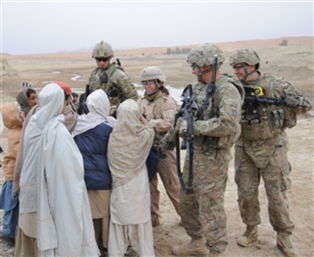 Members of Kandahar Provincial Reconstruction Team hand out pens to Afghan children during a site assessment of the Dowry Rud Check Dam in Kandahar province, Afghanistan, on Jan. 21, 2012.  The Provincial Reconstruction Team works with Afghan government officials at the district and provincial levels to build sustainable infrastructure capacity.  