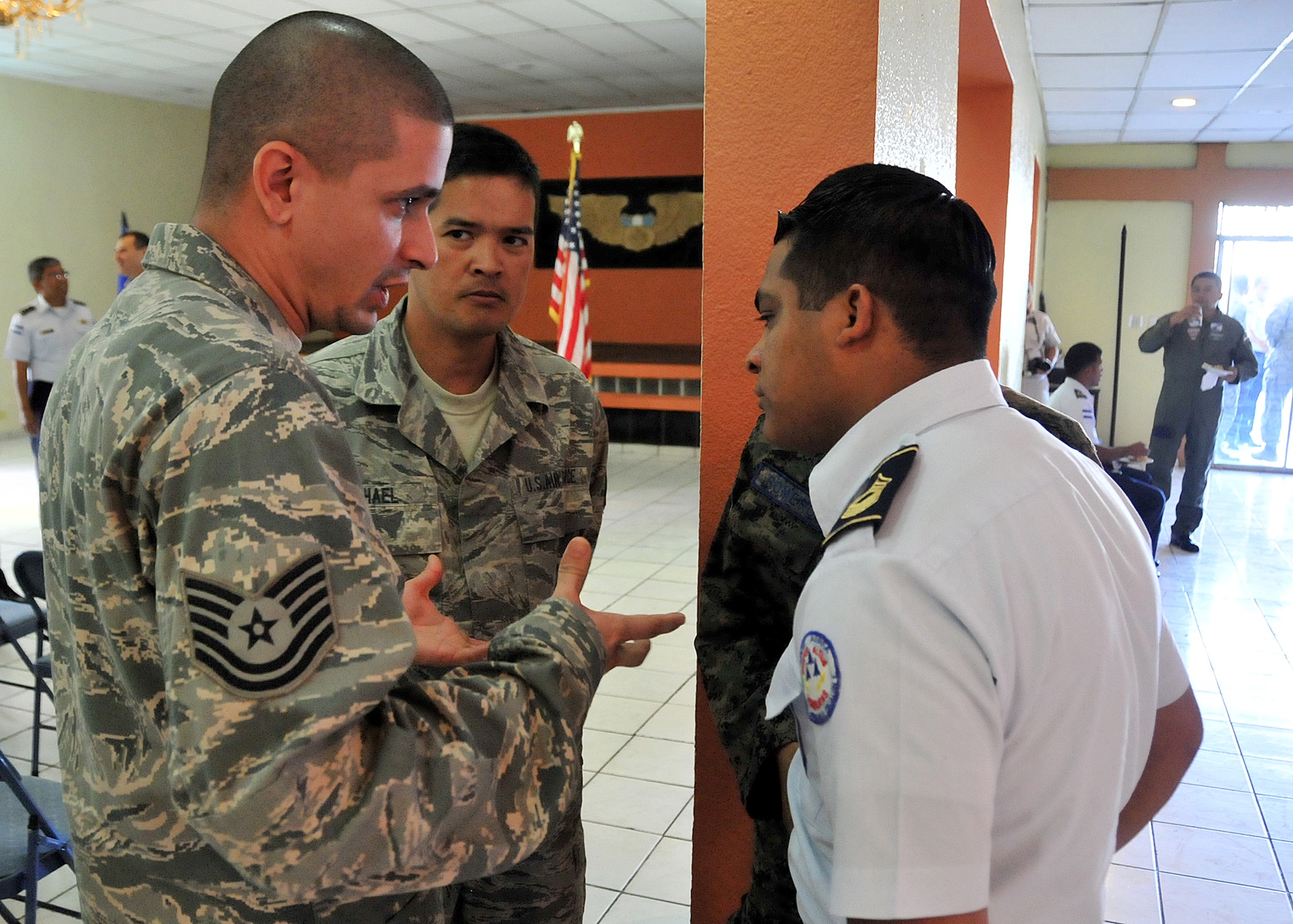 Master Sgt. Ronald Hael, 571st Mobility Support Advisory Squadron air advisor, listens as Tech. Sgt. Jason Lares, 571st Mobility Support Advisory Squadron power production craftsman, interacts with Airmen from the Honduran Air Force following the opening ceremony in Tegucigalpa, Honduras, Jan. 25.  Lares is one of MSAS translators on the mission.  (U.S. Air Force photo by Tech. Sgt. Lesley Waters)