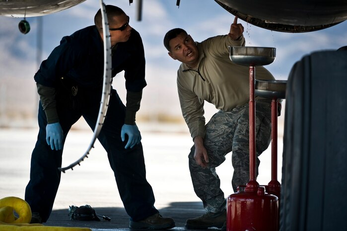 U.S. Air Force Staff Sgt. Jonathon Hill, 28th Aircraft Maintenance Squadron aerospace propulsion journeyman, Ellsworth Air Force Base, S.D., and Tech. Sgt. Randy Blumer, 28th AMXS aircraft hydraulics systems craftsman, identify a hydraulic pump leak underneath a B-1B Lancer during Red Flag 12-2 Jan. 24, 2012, at Nellis AFB, Nev. Red Flag is a realistic combat training exercise involving the air forces of the United States and its allies. The exercise is hosted north of Las Vegas on the Nevada Test and Training Range. (U.S. Air Force photo by Senior Airman Brett Clashman)