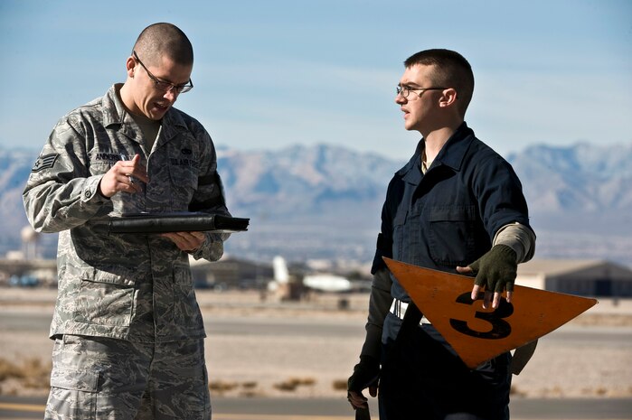 U.S. Air Force Staff Sgt. Chad Anderson, 28th Aircraft Maintenance Squadron quality assurance specialist, Ellsworth Air Force Base, S.D., and Senior Airman Jason Buckbee, 28th AMXS crew chief, discuss a B-1B Lancer's flight status during Red Flag 12-2 Jan. 24, 2012, at Nellis AFB, Nev. Red Flag is a realistic combat training exercise involving the air forces of the United States and its allies. The exercise is hosted north of Las Vegas on the Nevada Test and Training Range. (U.S. Air Force photo by Senior Airman Brett Clashman)
