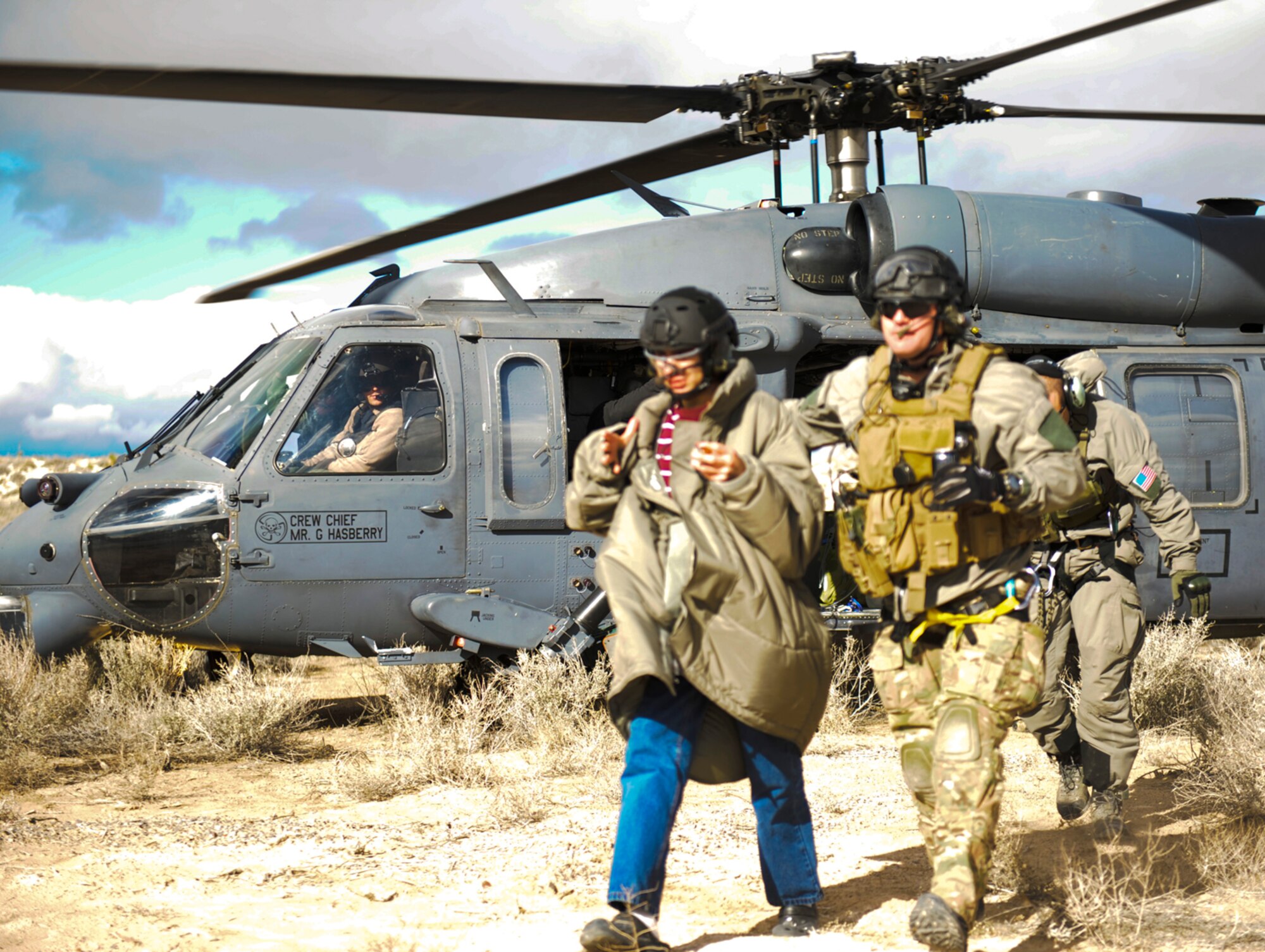 HOLLOMAN AIR FORCE BASE, N.M. -- U.S. Air Force Master Sgt. Chris Albrand, 512th Rescue Squadron pararescueman, escorts Angelo Baca from a HH-60 Pavehawk Jan. 16, from Kirtland Air Force Base, N.M. to be checked out at the White Sands National Monument Headquarters after a 15-hour search for the missing teen. Baca, who is autistic, wandered away from his family while they were visiting the National Monument. (U.S. Air Force Photo by Tom Fuller/ Released)