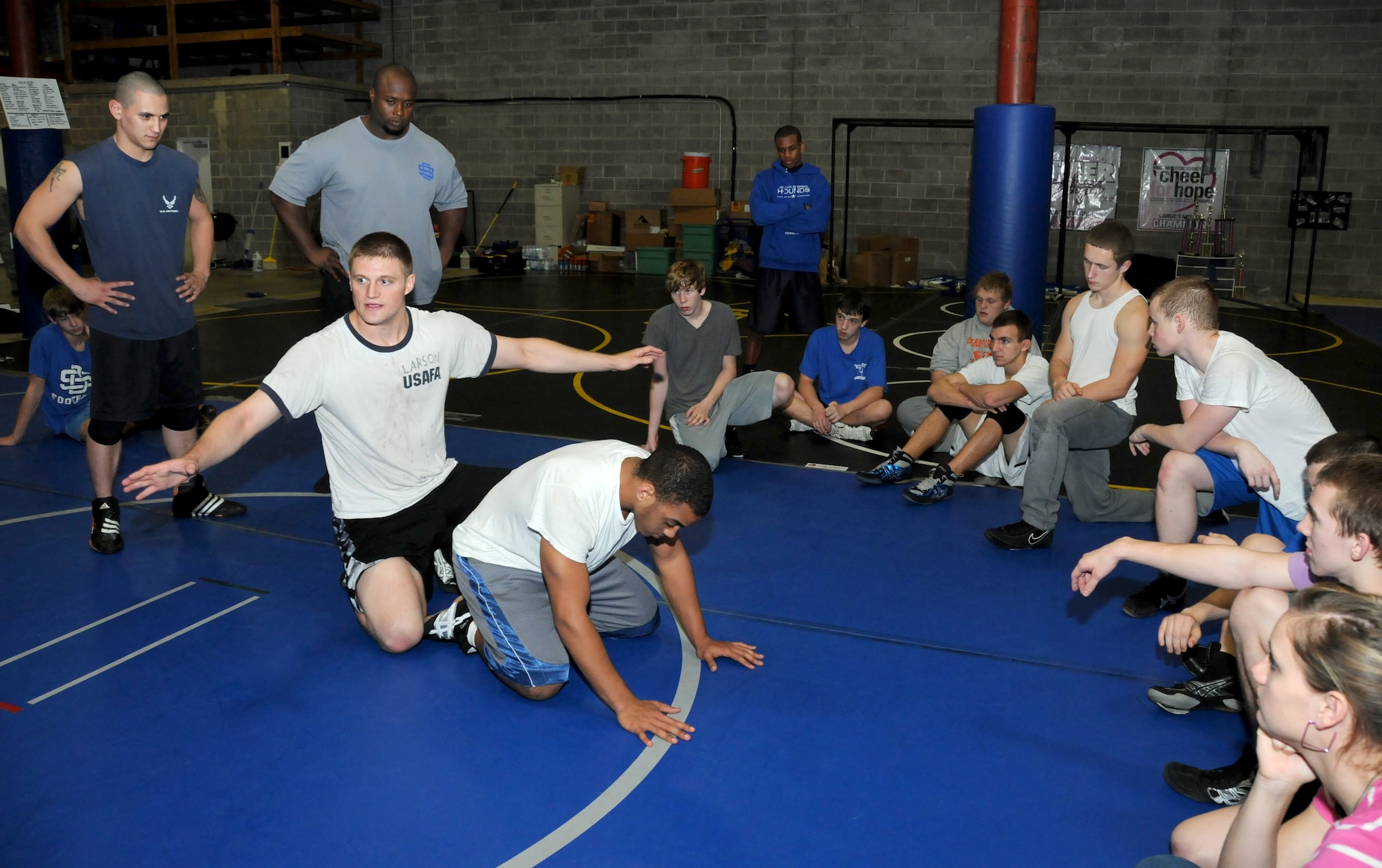 Staff Sgt. Thomas Rich, 338th Training Squadron, and Bryant Shaw, Ocean Springs head wrestling coach, watch as Second Lt. Josh Larson, 333rd Training Squadron, Keesler Air Force Base, Miss., prepares to demonstrate a tight waist arm chop wrestling move on an Ocean Springs High School student Aaron Esters, 17, during a practice session Jan. 24, 2012, at the athletic department warehouse on Highway 90 in Ocean Springs, Miss.  Rich and Larson are volunteers for the school’s wrestling program.  (U.S. Air Force photo by Kemberly Groue)
