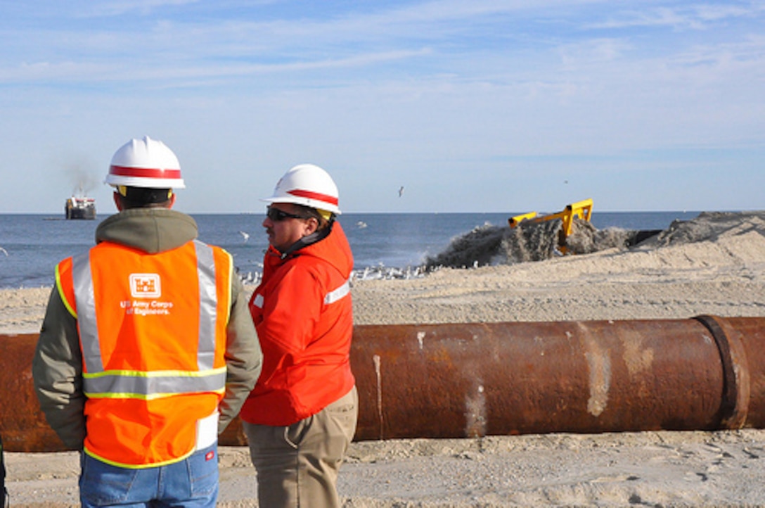 Coastal Engineer Donald Cresitello and Resident Engineer Paul Jalowski, both with the U.S. Army Corps of Engineers, New York District, chat as sand is pumped into place on Monmouth Beach, N.J.