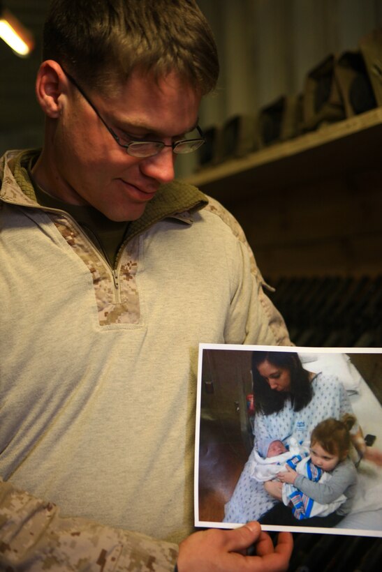 Cpl. Joseph Schank, a small arms repair technician with Marine Air-Ground Task Force Support Battalion 11.2, 2nd Marine Logistics Group (Forward), lovingly gazes at a photo of his wife, daughter and newborn son during his workday aboard Camp Leatherneck, Afghanistan, Jan. 27. Schank was able to watch his son’s birth while deployed in Afghanistan via video chat. (U.S. Marine Corps photo by Cpl. Katherine M. Solano)