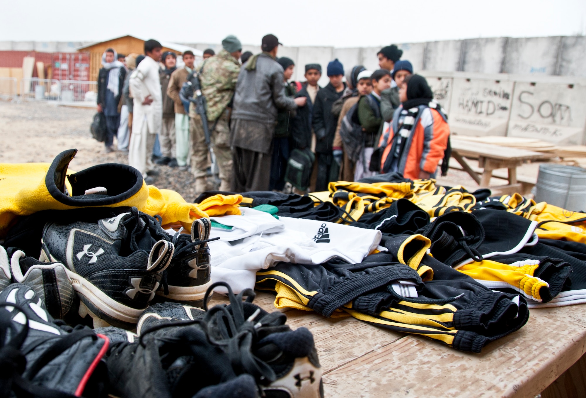 KANDAHAR AIRFIELD, Afghanistan -- Afghan children line up to receive soccer outfits and shoes from Lt. Col. Patrick Verdon, Tactical Air Control Center liaison officer, at the Kandahar Airfield bazaar school Jan. 21, 2012. Verdon conducted a drive for the donated items from his Morristown, N.J. soccer club. (U.S. Air Force photo by Staff Sgt. David Carbajal)