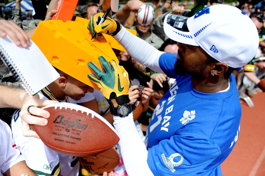Charles Woodson, a Green Bay Packers cornerback, signs a "cheese head" for Airman 1st Class Steve Ladwig, 8th Intelligence Squadron, during Pro Bowl practice at Earhart Field, Joint Base Pearl Harbor-Hickam, Hawaii, Jan. 26. After each practice session, the players spent time with the servicemembers and their families by signing jerseys, helmets, footballs, towels and even surf boards. (U.S. Air Force photo/Staff Sgt. Mike Meares)