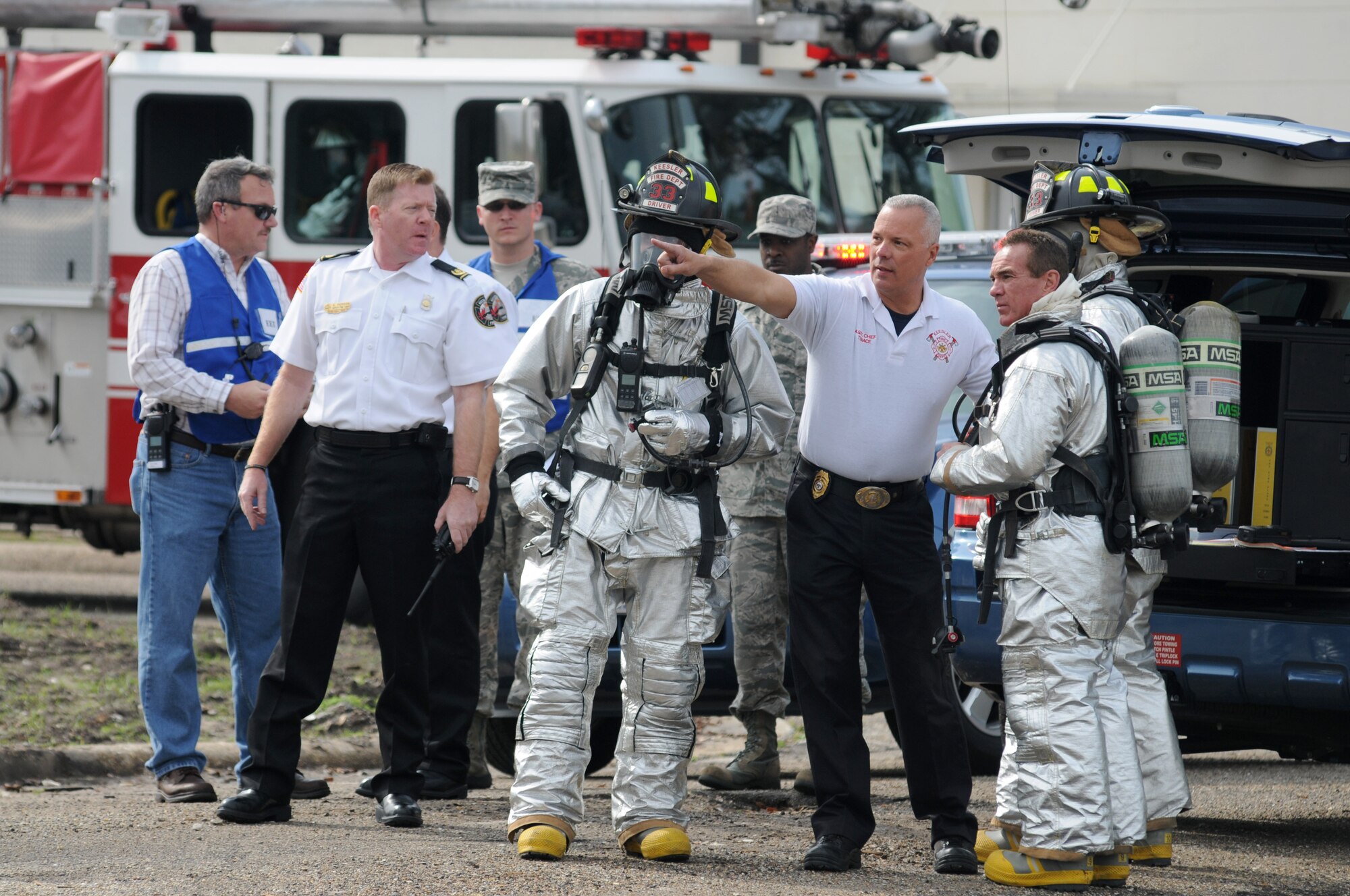 Assistant Fire Chief David Tenace, Keesler Fire Department, directs fire fighters at the scene of a Force Protection Condition exercise at Keesler Air Force Base, Miss., Jan. 26, 2012, while members of the Exercise Evaluation team observes their efforts.  The exercise was a Chemical, Biological, Radiological, Nuclear, and high-yield Explosive exercise with a scenario that included a terrorist group that was able to penetrate the base and park a truck with a four, hundred-gallon barrels full of anhydrous ammonia by the soccer field on G Street.  A small improvised explosive device was “exploded” causing the anhydrous ammonia to pour from the trailer, exposing a group of ten Airmen who had just finished physical training.  Immediately the Airmen simulated receiving skin and eye irritations and burns, coughing, chest pain and vomiting from exposure to the chemical.  Two Airmen also simulated receiving broken bones from flying debris from the explosion.   Also the 81st Medical Group and 81st Security Forces Squadron responded on scene.  The exercise took place Jan. 23-27.  (U.S. Air Force photo by Kemberly Groue)