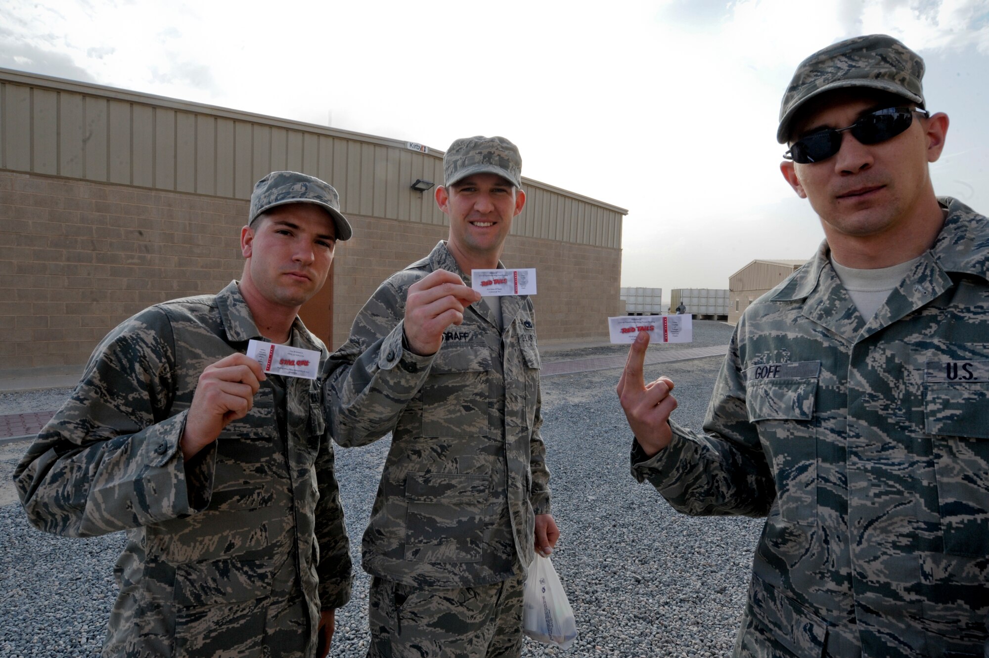 Senior Airman Benjamin Puhr, 332nd Expeditionary Maintenance Squadron, Staff Sgt. Nicholas Graff, 332nd Expeditionary Logistics Readiness Squadron, and Senior Airman Matthew Goff, also with the 332nd EMXS, hold out their tickets for the premiere showing of the movie "Red Tails" at an undisclosed location in Southwest Asia, Jan. 27, 2012. The tickets were donated by the East Coast Chapter of Tuskegee Airmen Inc. for 300 members of the 332nd Air Expeditionary Wing.  Puhr is native of Crystal River, Fla., Graff is a native of Clarksville, Tenn., and Goff's hometown is Williamson, W. Va., all are deployed from Shaw Air Force Base, S.C.(U.S. Air Force photo by Staff Sgt. Joshua J. Garcia/Released)