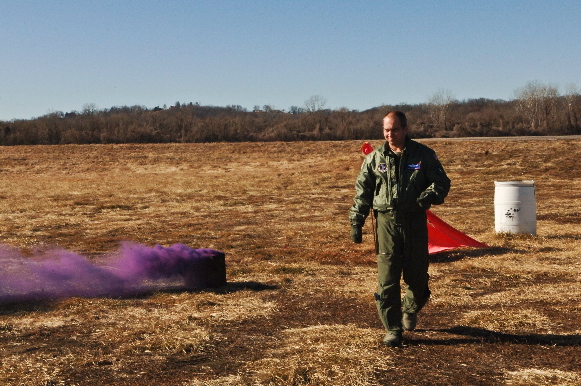 Master Sgt. Kent Bohart, Advanced Airlift Tactics Training Center instructor loadmaster, walks away after deploying a smoke grenade near Rosecrans Air National Guard Base, St. Joseph, Mo., Jan. 26, 2012. The smoke marks the point of impact for the combat airdrop. (Missouri Air National Guard photo by Tech. Sgt. Erin Hickok)