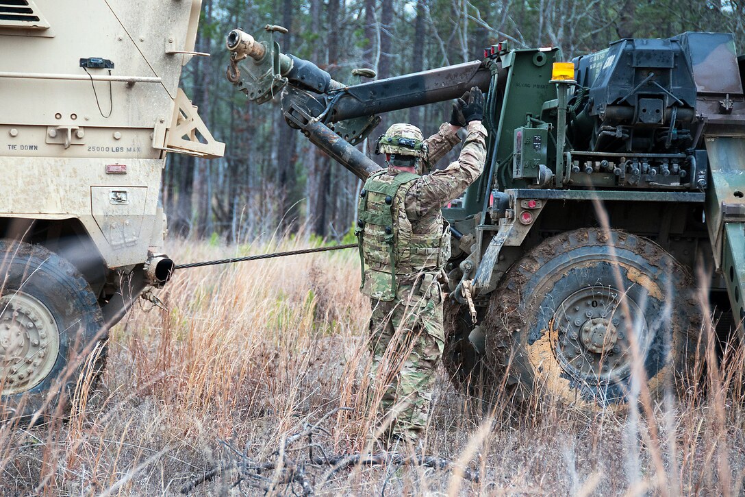 A paratrooper signals to a wrecker operator to stop as they pull a mine-resistant, ambush-protected vehicle from the mud at the Joint Readiness Training Center on Fort Polk, La., Jan. 25, 2012.