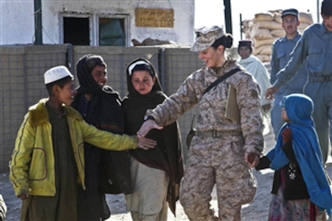U.S. Navy Petty Officer 2nd Class Kimberley Ryan holds hands with Afghan children as they walk to the local children's shura near Forward Operating Base Jackson in the Sangin district of Afghanistan's Helmand province on Jan. 20, 2012.  Ryan is the team leader assigned to the Marine Headquarters Group, Female Engagement Team.  The team, along with the 3rd Battalion, 7th Marine Regiment, have been conducting shuras, or classes, to provide area citizens with a variety of educational opportunities.  