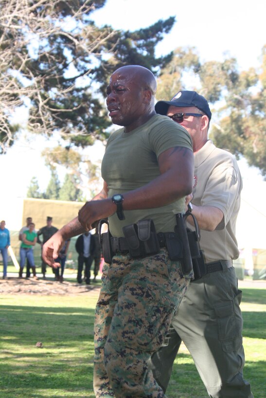 Sgt. Omar Askew, career planner, Headquarters and Service Battalion, is escorted to wash his eyes out after finishing the last station of the level one Oleoresin Capsicum spray course Jan. 27 aboard Marine Corps Recruit Depot San Diego. To complete the course the Marines had to complete five stations while having OC spray in their eyes. This course was to teach the Marines the effects of the spray and how to fight through the pain.
