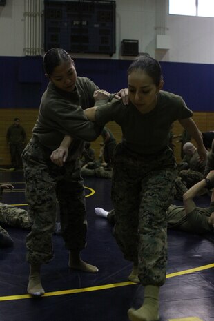 Lance Cpl. Jamie L. Mateo, a Headquarters and Headquarters Squadron maintenance air traffic controller, prepares to perform a takedown technique on Lance Cpl. Estephania de Leon, a H&HS Installation Personnel Administration Center administration clerk, during Auxiliary Security Forces training at the IronWorks Gym sports courts here Jan. 27. More ASF training is scheduled to take place this month.