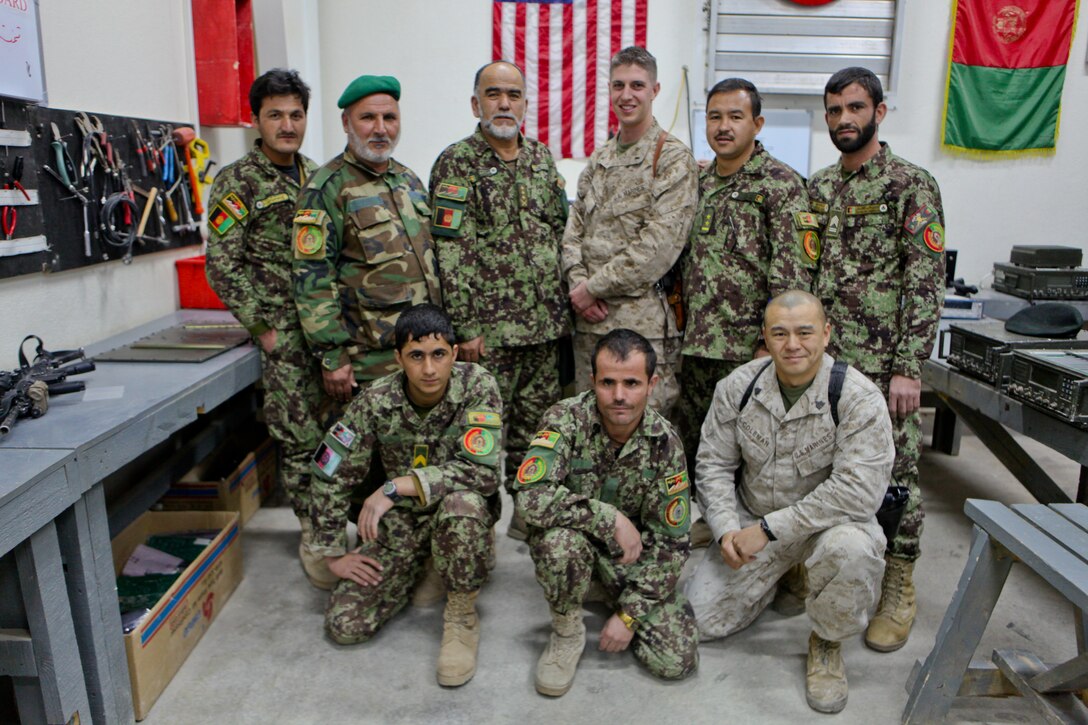 First Lt. Joseph M. Russell (top center), a Richmond Heights, Ohio, native and the advisor for the Afghan National Army’s 215th Corps communications officer, poses with soldiers with the 215th Corps communications section. Sergeant Alan Coleman (bottom right), a Fountain Valley, Calif., native and the enlisted advisor for the 215th Corps communications section, helped with Russell’s initiative to encrypt all of the radios within the 215th Corps. He advised the enlisted Afghan soldiers on how to build, clean, maintain and encode the encryption on all the radios. The team of approximately 20 soldiers serve the 14,000 member of the 215th Corps.::r::::n::::r::::n::::r::::n::