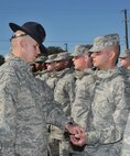 Basic Military Training Instructor Staff Sgt. Eddie Glover, presents Airman Basic Justus Sanchez with the Airman’s Coin, symbolic of a service member's transition from trainee to Airman, during Thursday’s presentation at Joint Base San Antonio-Lackland. Sanchez's mother, Airman Basic Lori Huayacla, who is in week two of basic training, was able to attend her son's coining and graduation ceremonies. (U.S. Air Force photo/Alan Boedeker)