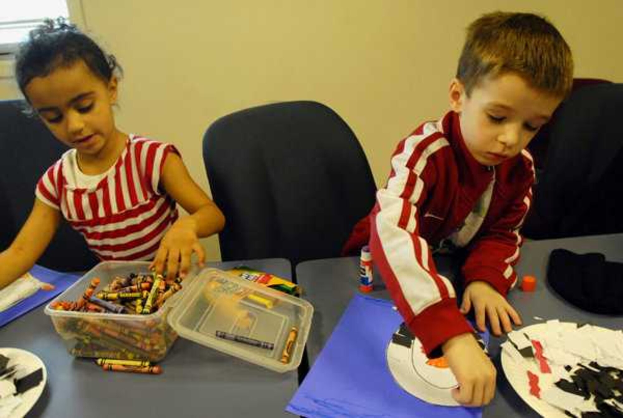 Amara Challinor, 4, left, and Kolten Collins, 5, use Crayons and color markers to decorate their paper mosaic penquins during Storytime at the McChord Library Jan. 12 at Joint Base Lewis-McChord, Wash. (U.S. Air Force courtesy photo/Scott Hansen)