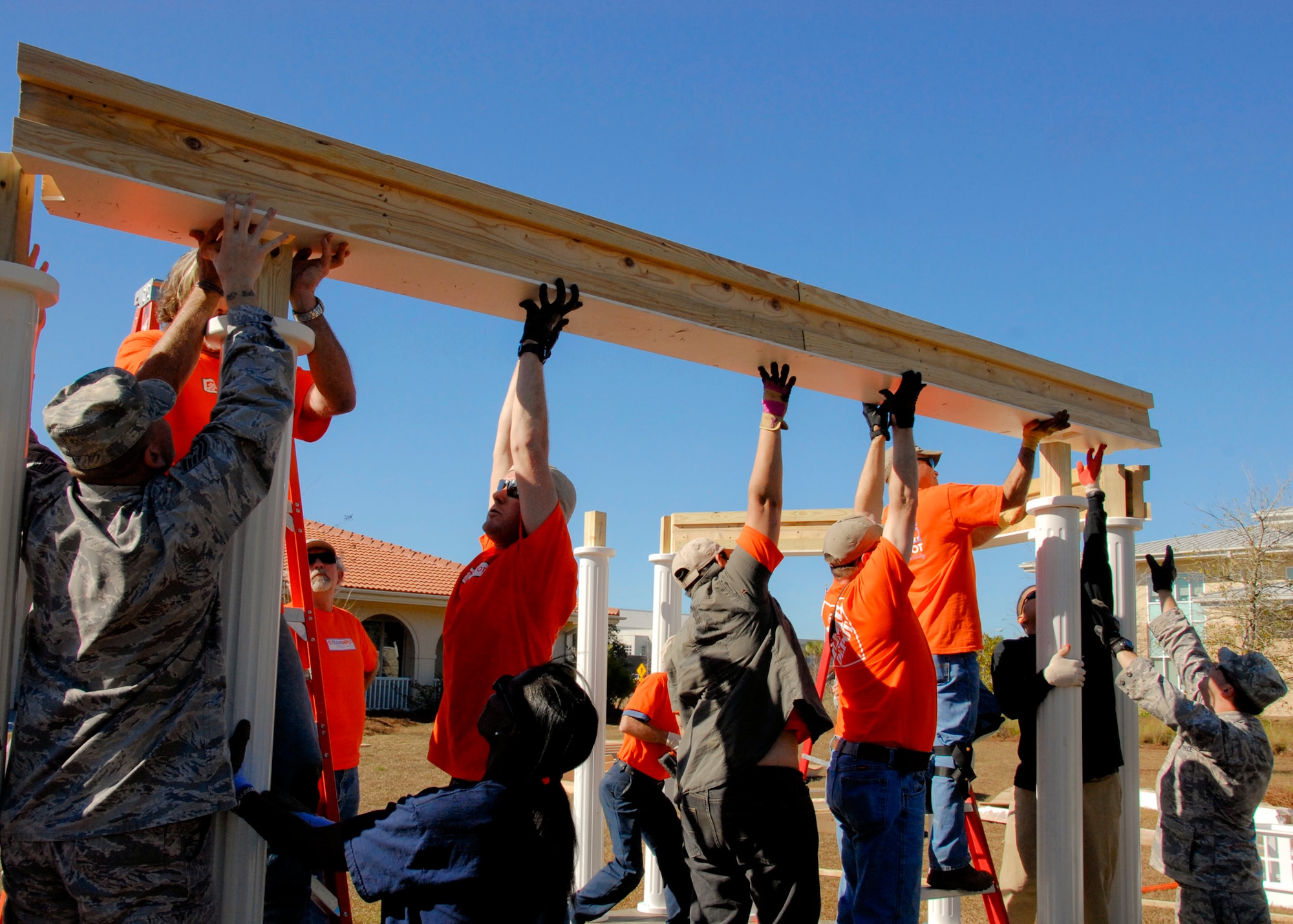 Tech Sgt. Shannon Calhoun, (left) and Sgt. Jacob Stull (far right), members of the 33rd Aircraft Maintenance Squadron, assist volunteers in placing a part of the roof on the new Fisher House gazebo Jan. 27.  The $10,000, 10- by 20-foot gazebo was donated by retired Air Force Col. Bill Mann and his family.  The Fisher House is one of a network of donated comfort homes built on major military bases and Veterans Administration centers, where families can stay while a loved one is receiving medical treatment.  (U.S. Air Force photo/Kevin Gaddie)