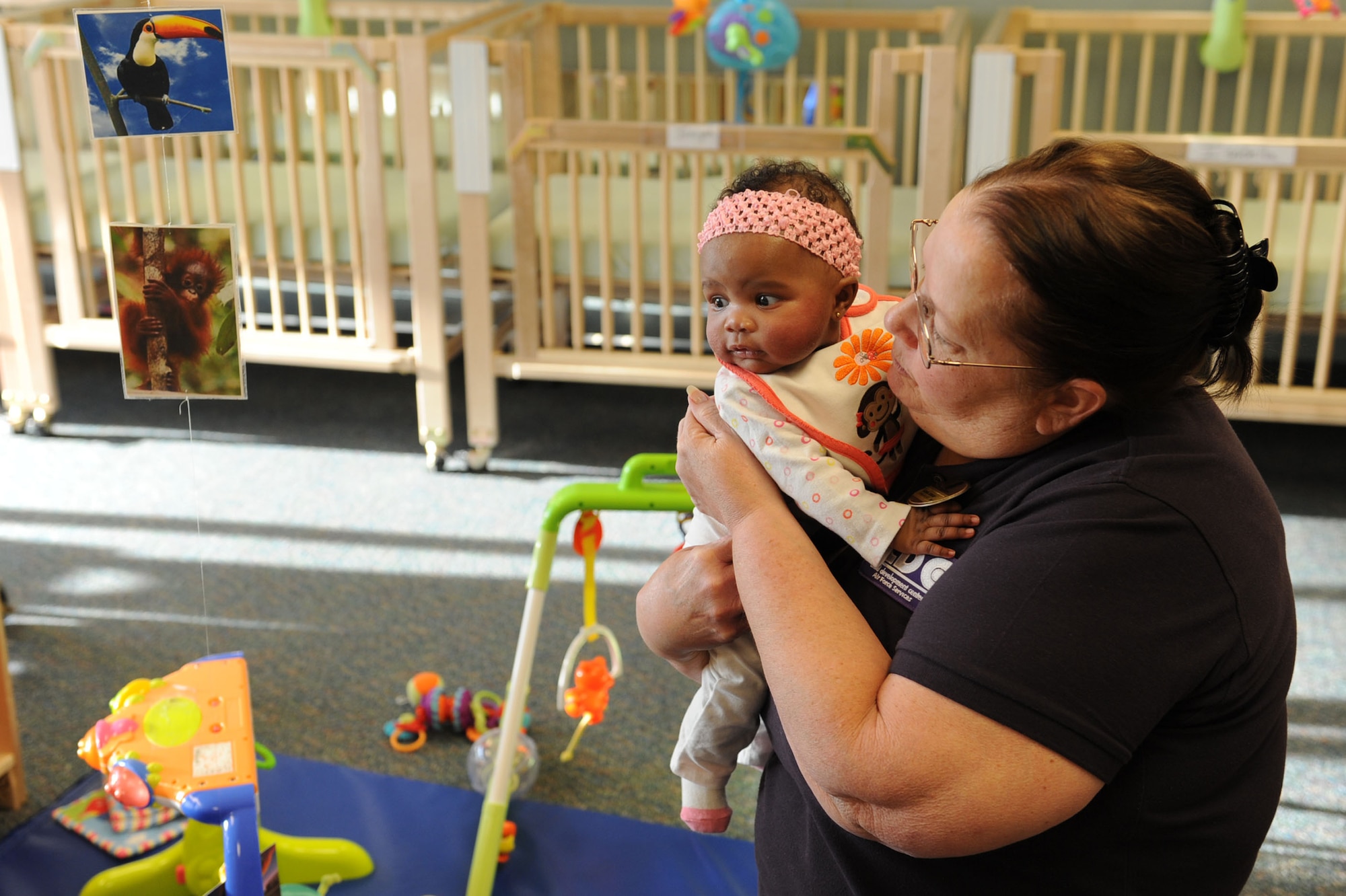 Marsha Johnson, Nellis Child Development Center II caregiver, plays with Janiyah Charles, daughter of U.S. Air Force Senior Airman Ashley Charles, 99th Force Support Squadron services fitness specialist, and Senior Airman Michael Charles, 99th Air Base Wing Public Affairs Journeyman, Jan. 27, 2012, at the newly built CDC II on Nellis Air Force Base, Nev. The CDC II opened Jan. 23, 2012, and is dedicated to provide care for 64 infants. (U.S. Air Force photo by Staff Sgt. Taylor Worley)
