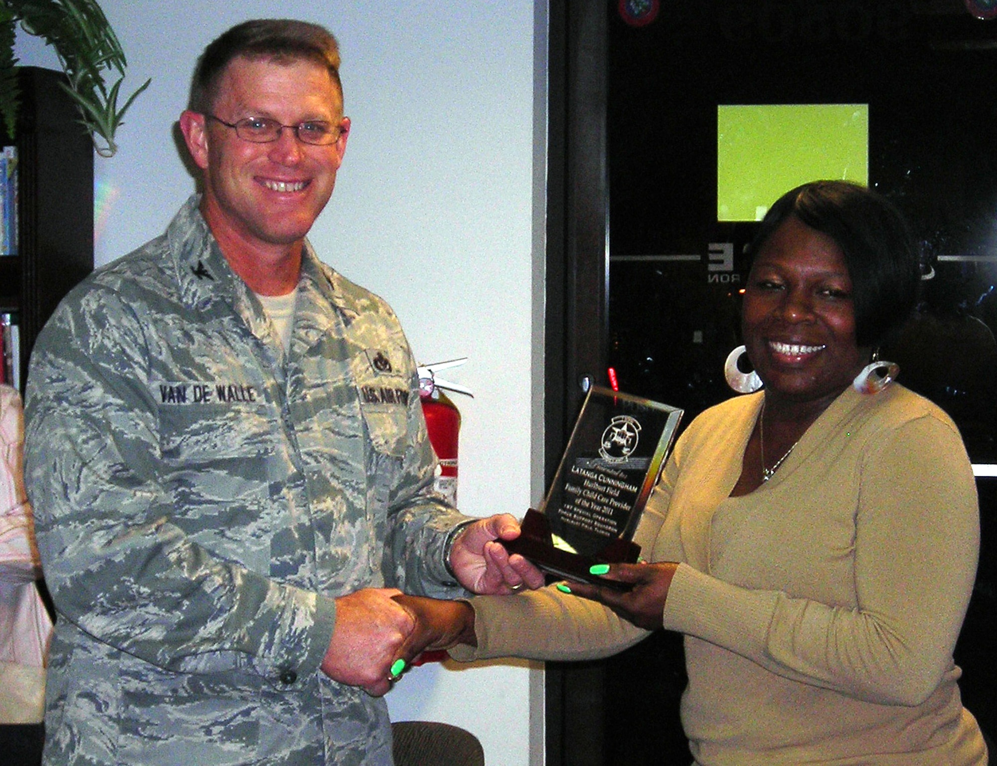 Latanga Cunningham, a Family Child Care provider, receives the Family Child Care Provider of the Year award from Air Force Col. Curt Van De Walle, commander of 1st Special Operations Mission Support Group.  The provider of the year award winner is selected primarily based upon positive FCC parent feedback. (Air Force photo by Airman 1st Class Hayden K. Hyatt/Released)