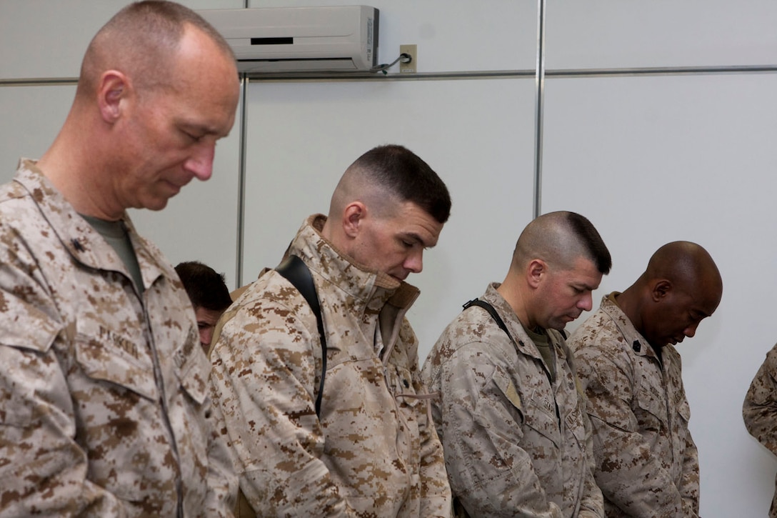 Service members, with 2nd Marine Aircraft Wing (Forward), bow their heads in prayer during a dedication of the Flightline Memorial Chapel at Camp Bastion, Afghanistan, Jan. 31. The ceremony was in remembrance of the U.S. Marine lives lost while supporting Marine Corps aviation in Afghanistan.