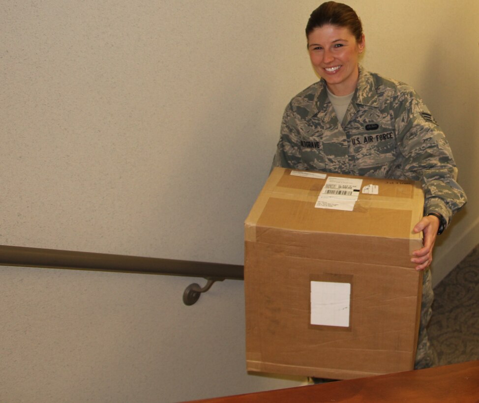 Senior Airman Tammy Holtgrave carries a delivery headed for the wing public affairs office. Holtgrave helped PA staff members move several boxes of new PA equipment.  She is a knowledge operations apprentice and recently began seasoning training at the 932nd Airlift Wing. (U.S. Air Force photo/Maj. Stan Paregien)