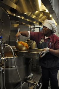 Ramona McNeil, a food service cook at the Rainbow Row Galley at Joint Base Charleston-Weapons Station scoops Creole Macaroni into serving pans, Jan. 26. More than 140 Goodwill employees, hired through the AbilityOne program, contribute to the overall success of the five-star rated dining facility by prepping, cooking, cleaning and serving food to service members. The AbilityOne program is a federal initiative that helps people who are blind or have other significant disabilities find employment by working within a national nonprofit agency that sell products and services to the U.S. government. (U.S. Navy photo/Petty Officer 1st Class Jennifer Hudson)