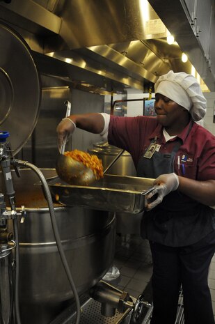 Ramona McNeil, a food service cook at the Rainbow Row Galley at Joint Base Charleston-Weapons Station scoops Creole Macaroni into serving pans, Jan. 26. More than 140 Goodwill employees, hired through the AbilityOne program, contribute to the overall success of the five-star rated dining facility by prepping, cooking, cleaning and serving food to service members. The AbilityOne program is a federal initiative that helps people who are blind or have other significant disabilities find employment by working within a national nonprofit agency that sell products and services to the U.S. government. (U.S. Navy photo/Petty Officer 1st Class Jennifer Hudson)