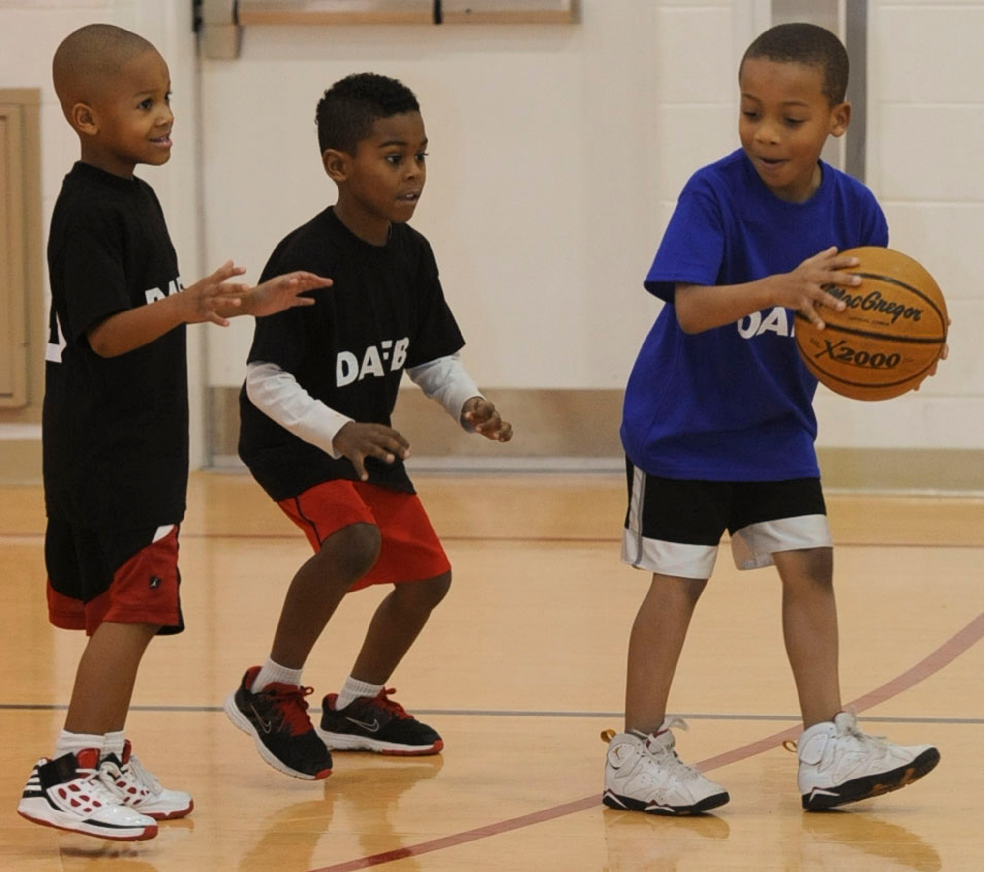 Anthony Scott, right, dribbles next to two defenders during a game Jan. 27, 2012, at the Dover Air Force Base, Del., Youth Center. The game was part of the Youth Center's youth Basketball league which helps teach the children the fundamentals of the game. (U.S. Air Force photo by Senior Airman Matthew Hubby)
