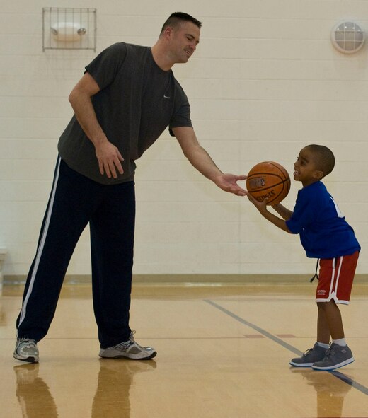 Duane Haught, left, a volunteer coach, hands a basketball to Brandon Freeman during a shooting drill before the start of a game Jan. 27, 2012, at the Dover Air Force Base, Del., Youth Center. The Youth Center hosts the games as part of its youth Basketball league, which is run by volunteers.  (U.S. Air Force photo by Senior Airman Matthew Hubby)