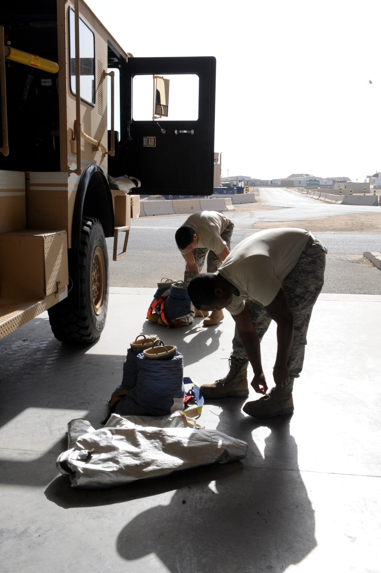 Senior Airman Courtland Dickerson and Tech. Sgt. Daniel Cruz, 332nd Expeditionary Civil Engineer Squadron firefighters, change into their fire retardant suits prior to responding to a mass casualty exercise at an undisclosed location in Southwest Asia, Jan. 30, 2012. The exercise tested first responders on their capability to handle possible real world situations. Dickerson is a native of Griffin Ga., and Cruz is a native of Santa Rita, Guam. Both are deployed from Joint Base Pearl Harbor-Hickam, Hawaii.(U.S. Air Force photo by Staff Sgt. Joshua J. Garcia/Released)