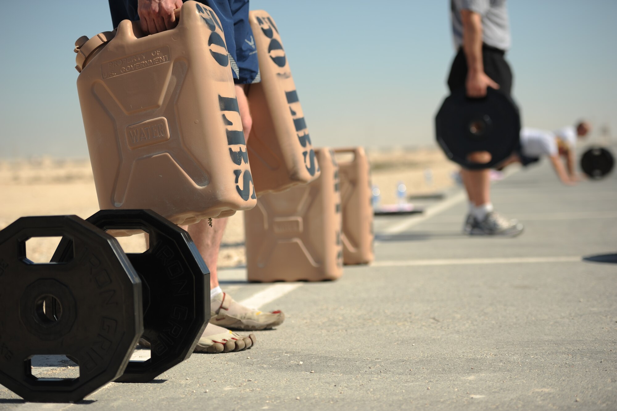 SOUTHWEST ASIA – Senior Airman Brent Borkey, 379th Expeditionary Maintenance Squadron and native of Winston-Salem, N.C., shoulder-shrugs 50-pound water cans during a new fitness program here Jan. 27, 2012. Staff Sgt. Roberto Salinas created the program for people who wanted to incorporate a variety of exercises into one fitness regimen. (U.S. Air Force photo/Staff Sgt. Nathanael Callon)