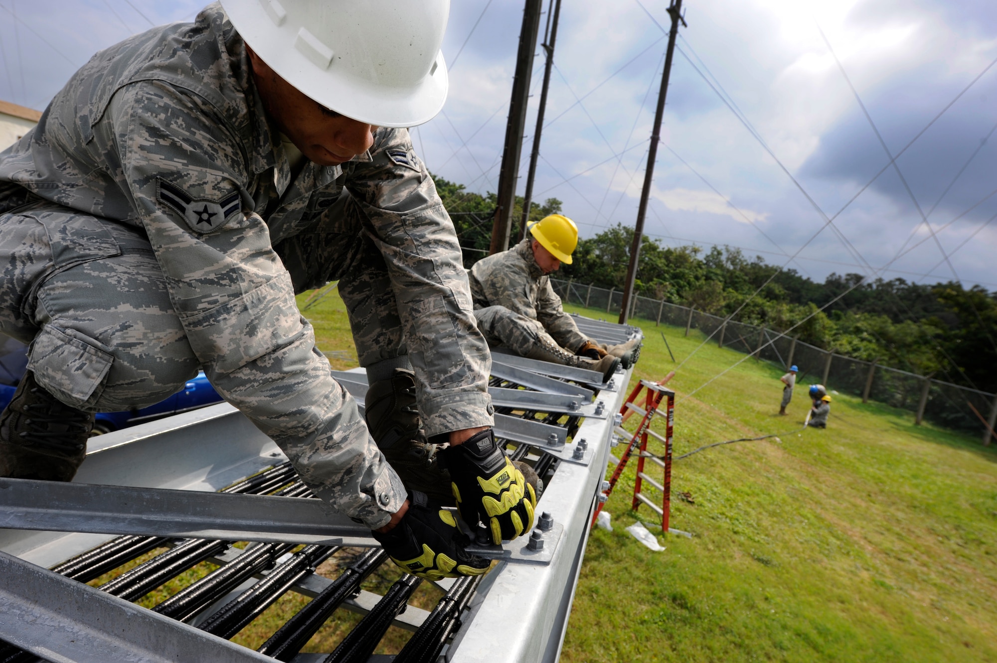 U.S. Air Force Airmen 1st Class Jeshod Hughes and James Behr, both 18th Communications Squadron cable and antenna systems technicians, bolt down wire covers leading to an air-to-ground communication transmission tower on Kadena Air Base, Japan, Jan. 30. The cable and antenna systems shop is upgrading the tower to give the tower more reliability and air traffic controllers more radio frequencies. (U.S. Air Force photo by Airman 1st Class Maeson L. Elleman/Released)