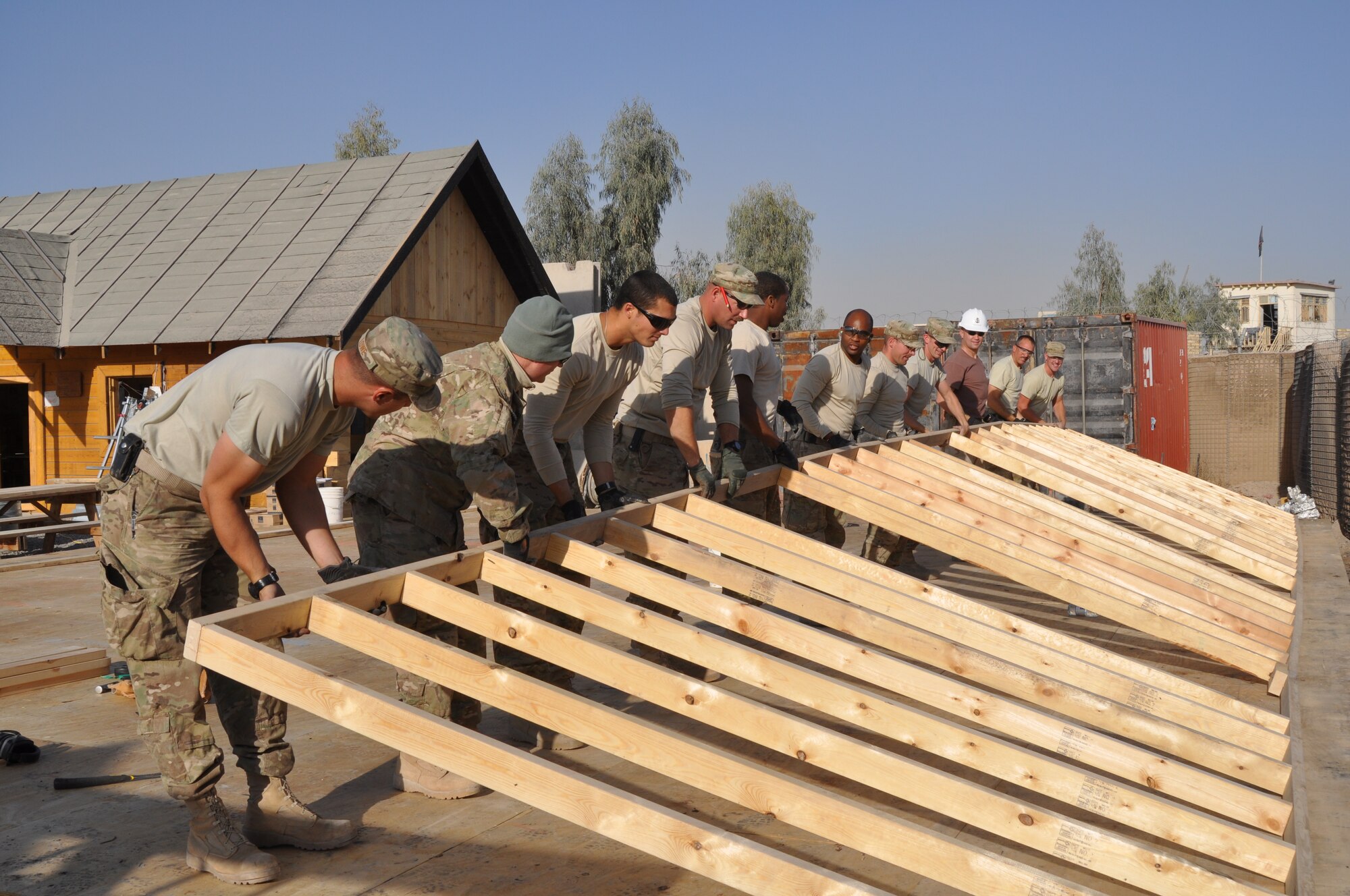 KANDAHAR AIRFIELD, Afghanistan -- Volunteers from the 809th Expeditionary RED HORSE Squadron and 30th Naval Construction Regiment lift up a wall for the bazaar school Dec. 18, 2011. The new bazaar school reopened Jan. 21, 2012. (U.S. Air Force photo by Capt. Passion Julinsey)