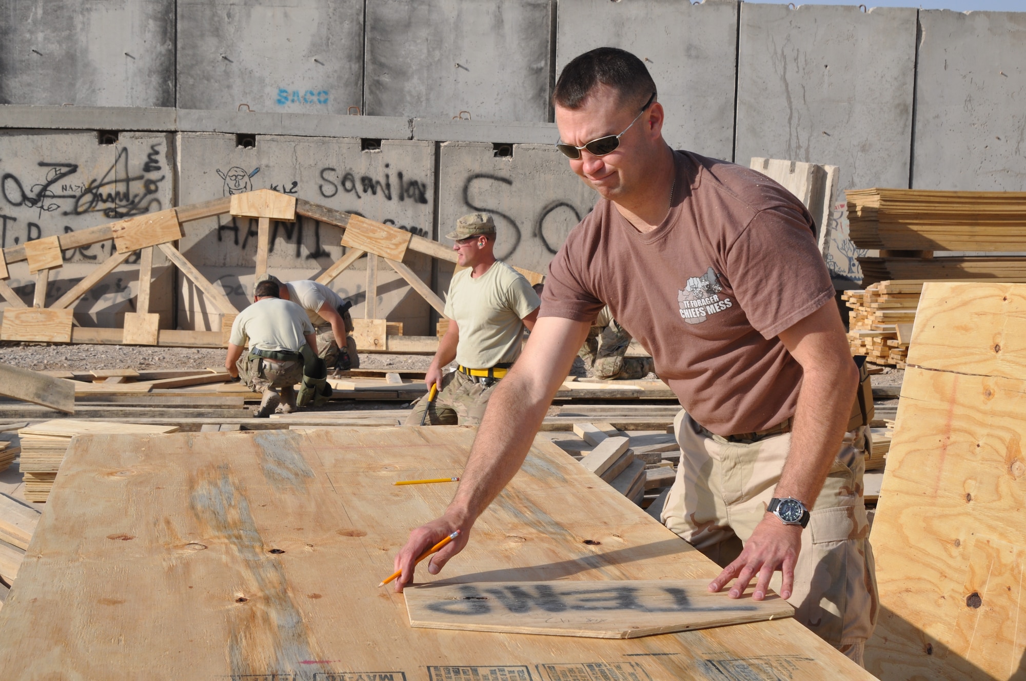 KANDAHAR AIRFIELD, Afghanistan -- Chief Petty Officer William Kettle, 30th Naval Construction Regiment builder, traces gusset plates on plywood donated by the Canadian forces. Kettle is one of the Seabees who volunteered to build the school that reopened Jan. 21, 2012. (U.S. Air Force photo by Capt. Passion Julinsey)