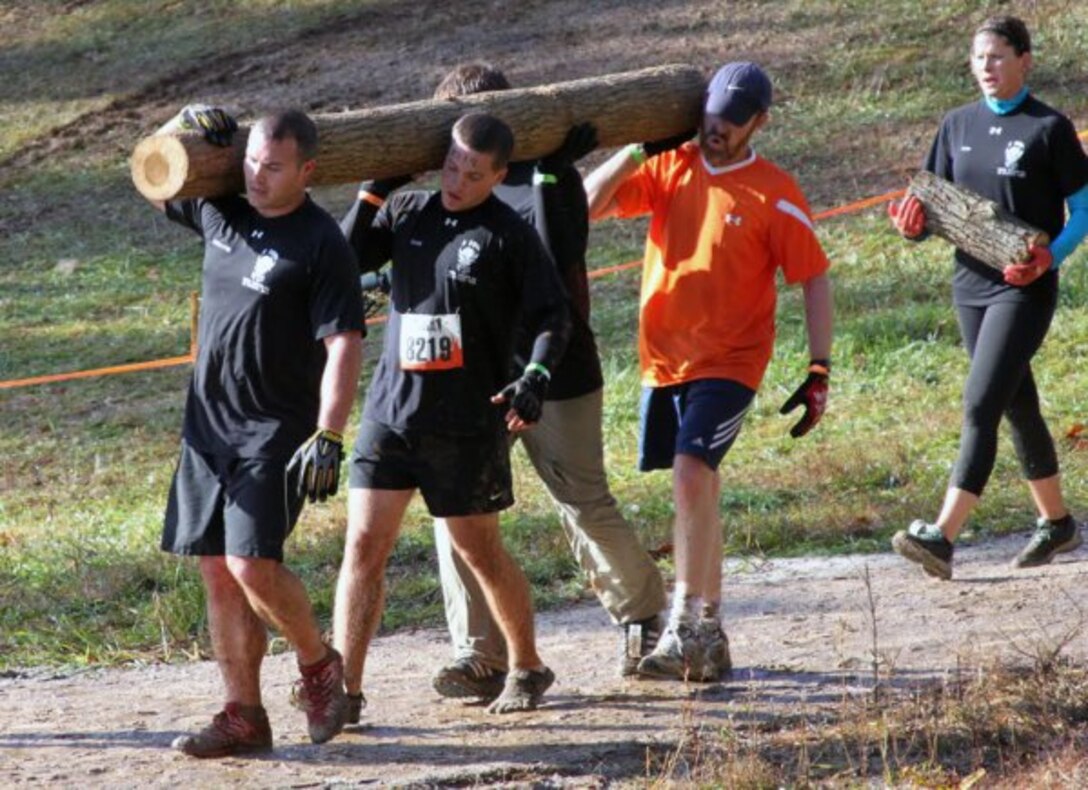 VIRGINIA -- Pete DeMattei (left), and Blake Burd (right), U.S. Army Corps of Engineers Middle East District, carry a log up and down a hill with teammates during one of the 25 obstacles on the course. Seven U.S. Army Corps of Engineers Middle East District employees were part of a large team that participated in the 10-mile endurance event to honor a fallen Navy SEAL and raise money for the Wounded Warrior Project.