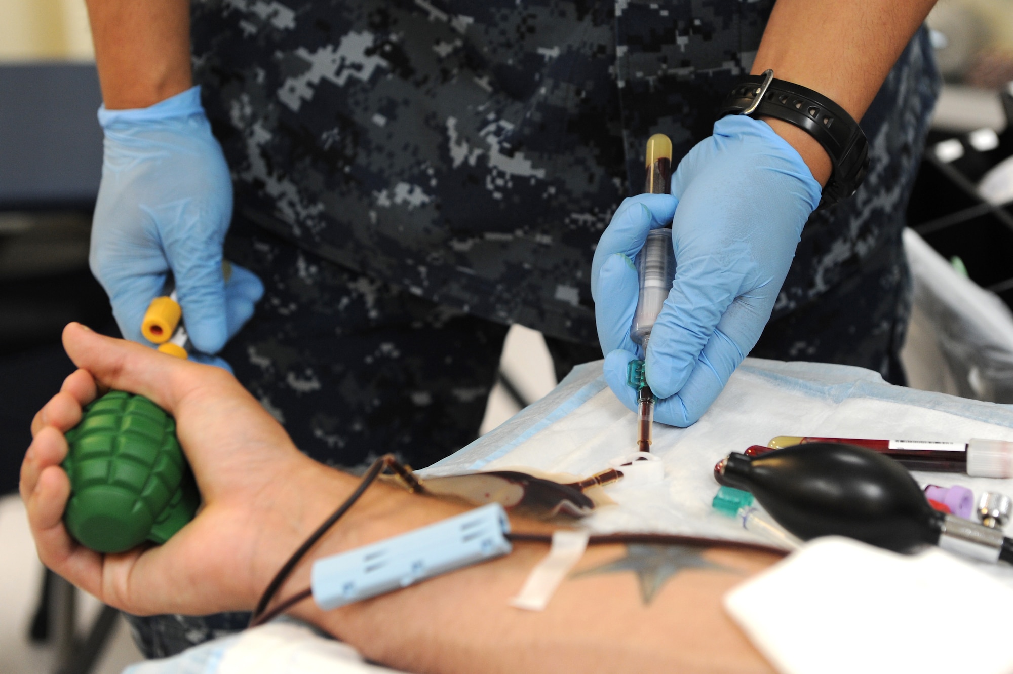 Airman 1st Class Michale Smith, 18th Logistics Readiness Squadron First-Term Airman Center student, holds his arm still as U.S. Navy Petty Officer 1st Class Jun Villanueva , hospital corpsman from the U. S. Naval Hospital Camp Lester, puts the needle in his arm during the blood drive on Kadena Air Base, Japan, June 27, 2012. The blood drive begins with registration, vital signs, screenings, bag issue, phlebotomy/blood donation and donor recovery with lunch provided. FTAC students receive a briefing prior to donating blood that determines their eligibility to donate blood. The Armed Services Blood Bank Center supports those serving in the Pacific and insures the donated blood is available for the Pacific operational mission, active-duty members, their family and Department of Defense personnel. (U.S. Air Force photo/Junko Kinjo)
