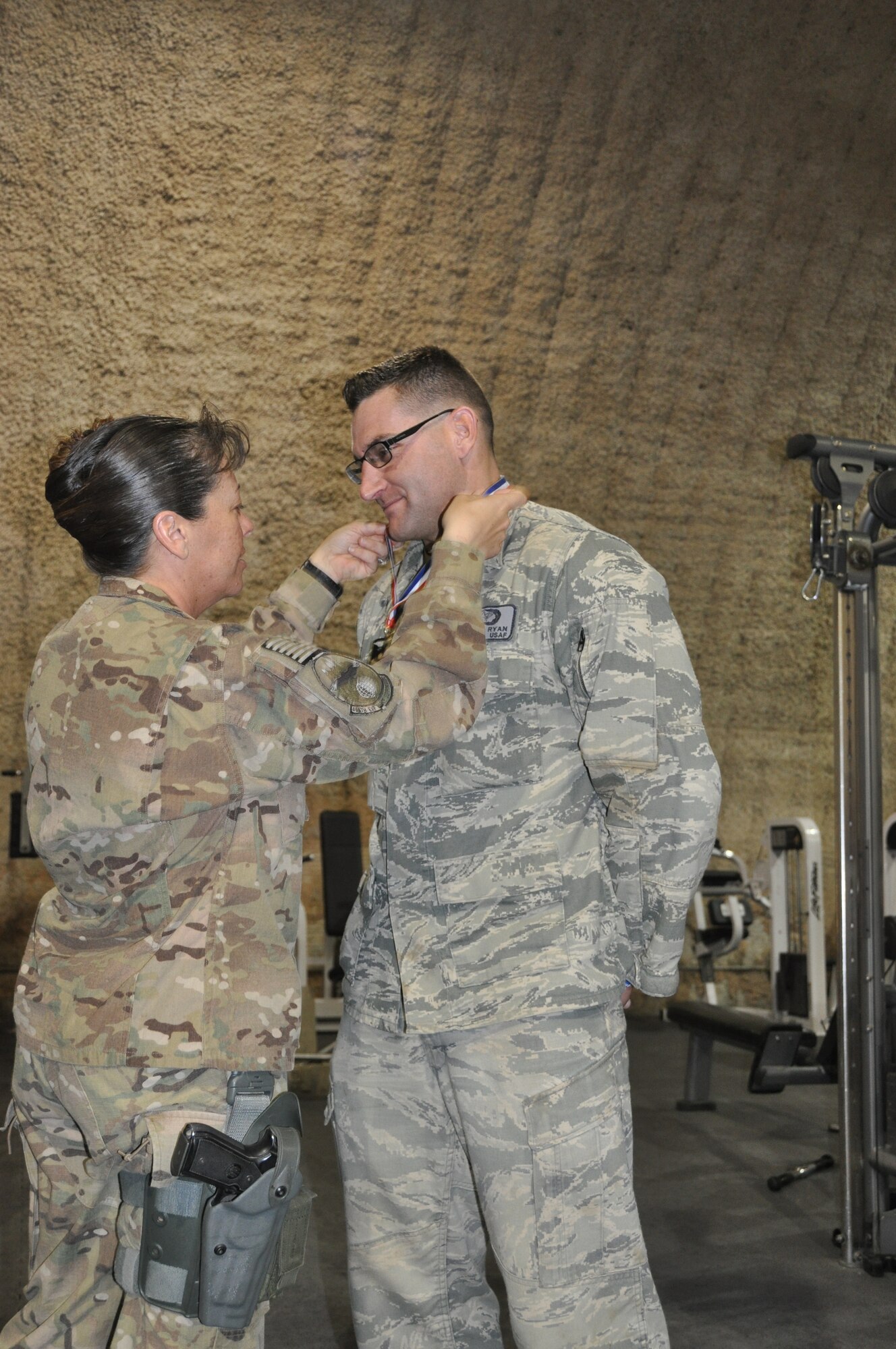 Lt Col Katrina Stephens (left), 455th Expeditionary Force Support Squadron commander, presents the "strongest in the AOR" 1st place medal to TSgt Ryan Callagy, member of 455th Expeditionary Civil Engineer Squadron, Bagram Airfield, Afghanistan. Bagram-assigned Airmen recently bested more than 40 other competitors to earn the title "strongest in the AOR." (U.S. Air Force photo/TSgt Shawn McCowan)